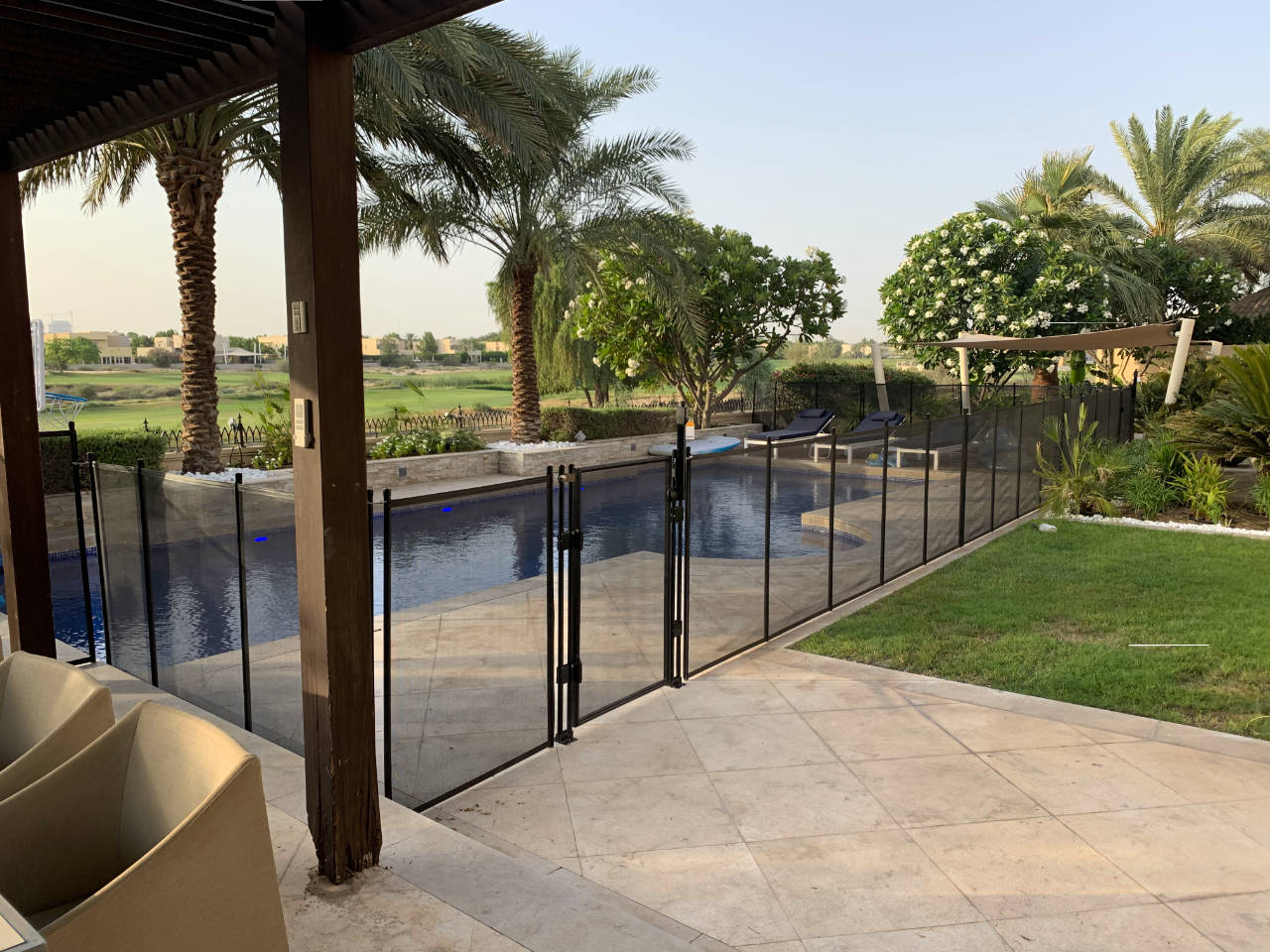 Mirador La Coleccion | AMANANET Pool area with a glass safety fence, palm trees, and lounge chairs in a sunny backyard.